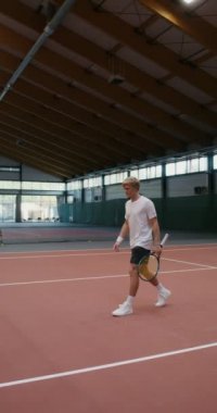 Bir erkek ve bir kadın tenis kortunun ortasında gerilmiş bir ağın üzerinden el sıkışıyor.