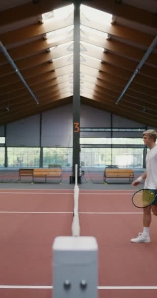 Mann und Frau geben sich inmitten eines Tennisplatzes die Hand über ein gespanntes Netz — Stockvideo