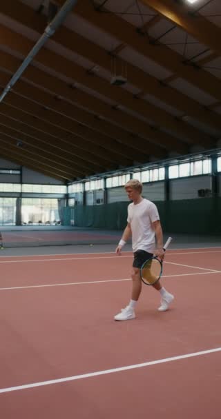 En man och kvinna skakar hand över ett sträckt nät mitt på en tennisbana — Stockvideo