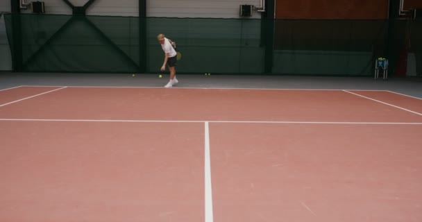 En manlig tennisspelare gör en stark slå bollen med en racket — Stockvideo