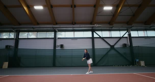 Genç bir kadın profesyonel tenis oynuyor, tenis topuna raketle vuruyor. — Stok video