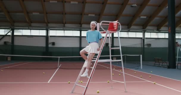 Žena tenista sedí na schodech z křesla rozhodčích a dívá se do kamery — Stock video