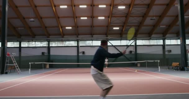 Giovane uomo e donna giocare a tennis sul campo da tennis al coperto, colpendo colpo dopo colpo — Video Stock