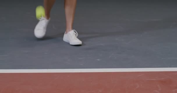 Primer plano, piernas de una joven jugadora de tenis en zapatillas blancas, durante un partido — Vídeos de Stock