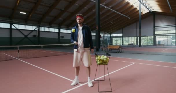 Un joven llena una pelota de tenis con raqueta — Vídeos de Stock