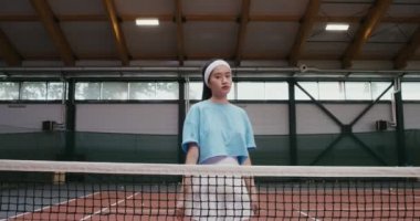 Tenis oyuncusu bir tenis ağına yaslanmış poz veriyor.