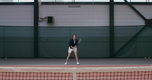 Een vrouw atleet speelt tennis, subtiel afstotende slag na slag met een racket — Stockvideo