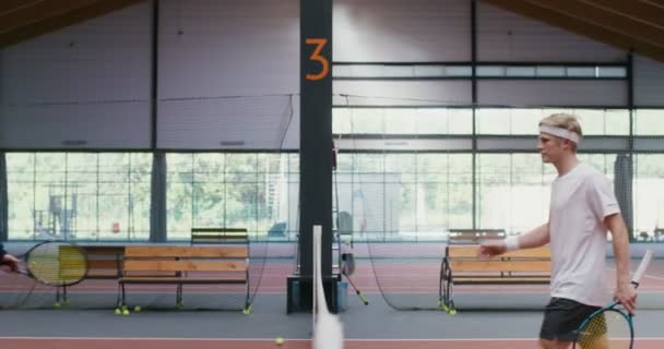 Twee mannen groeten elkaar, schudden elkaar de hand over het net en gaan tennissen. — Stockvideo