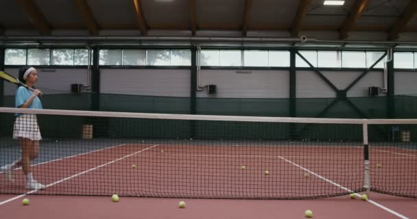 Una jugadora de tenis con raqueta de tenis posando apoyada en una red de tenis — Vídeo de stock