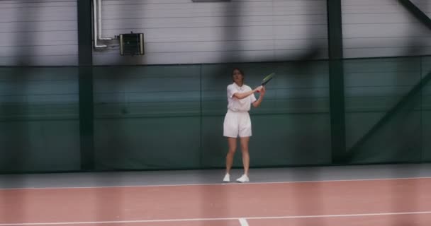 En kvinnlig tennisspelare spelar tennis, slår bollen om och om igen — Stockvideo