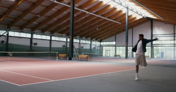 Joven hombre y mujer jugar al tenis en pista de tenis cubierta, golpe tras golpe — Vídeo de stock