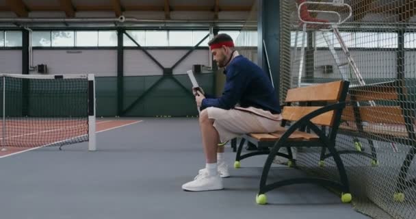 Un joven envuelve el mango de una raqueta de tenis con una cinta especial — Vídeos de Stock