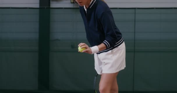 Een vrouw begint een tenniswedstrijd door de bal te gooien en te slaan met een racket — Stockvideo