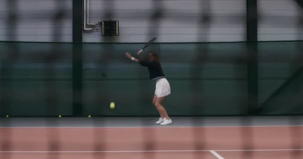 Mulher jogador de tênis salta, batendo uma bola de tênis com uma raquete — Vídeo de Stock