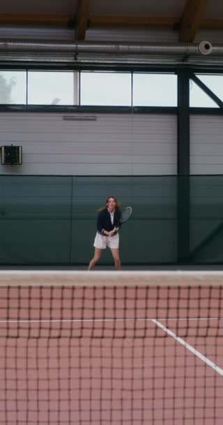 Женщина-теннисистка прыгает, ударяя теннисный мяч ракеткой — стоковое видео