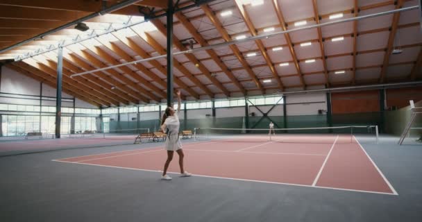 Los atletas se lanzan la pelota unos a otros a través de una red estirada en el centro de la sala — Vídeo de stock