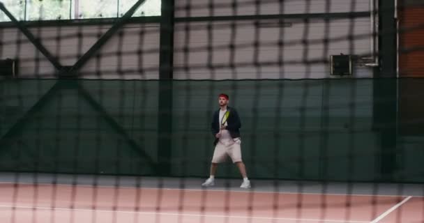 Un homme joue au tennis, frappant la balle avec une raquette encore et encore — Video