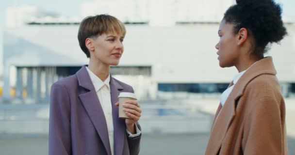 Африканська американська жінка та європейська жінка спілкуються на відкритому повітрі. — стокове відео