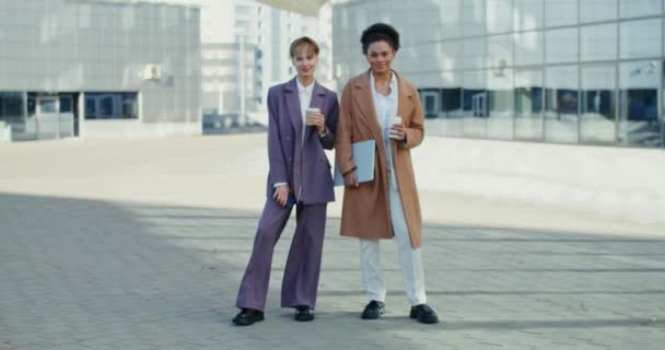 Two business women are looking at the camera, standing near the business center — Stock Video