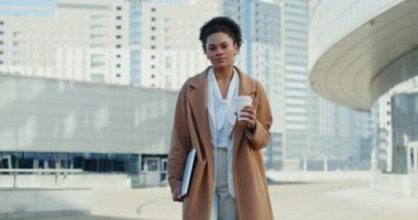 Afrika kökenli Amerikalı iş kadını bir şehrin iş merkezinde yürüyor.