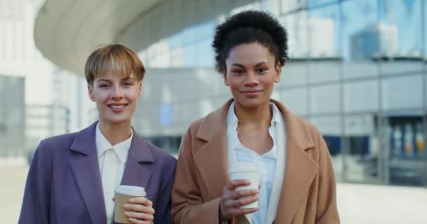 Dos mujeres de negocios están mirando a la cámara, de pie cerca del centro de negocios — Vídeos de Stock