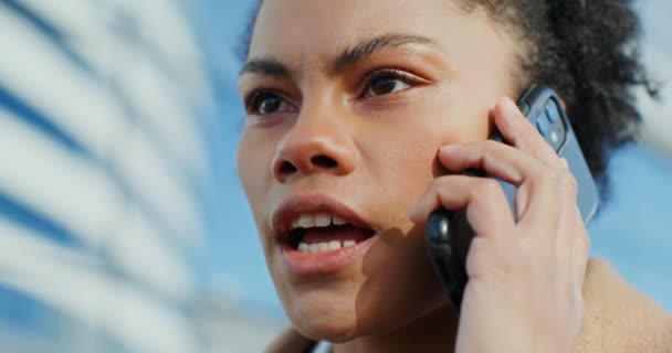 アフリカ系アメリカ人の女性が屋外で真剣な表情で携帯電話で話しています — ストック動画