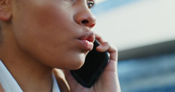 En afrikansk amerikansk kvinna pratar på en mobiltelefon med en seriös blick utomhus — Stockvideo