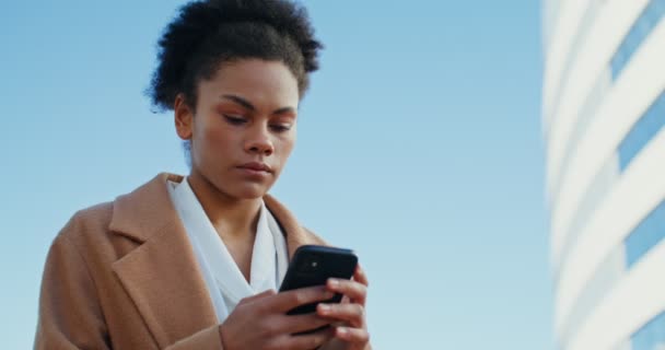 Афроамериканка пользуется мобильным телефоном на открытом воздухе — стоковое видео