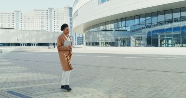 Seorang wanita african Amerika berjalan melalui pusat kota dan tersenyum — Stok Video