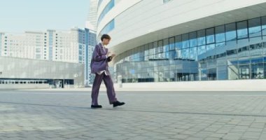 İş elbisesi giymiş bir kadın açık havada ekrana dokunmak için tablet kullanıyor.