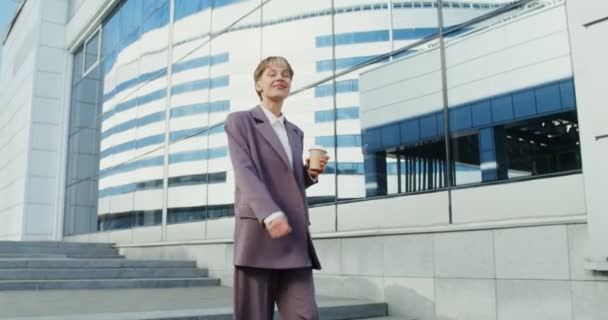 Eine Frau lächelt, während sie die Treppe zwischen modernen Bürogebäuden hinuntergeht — Stockvideo