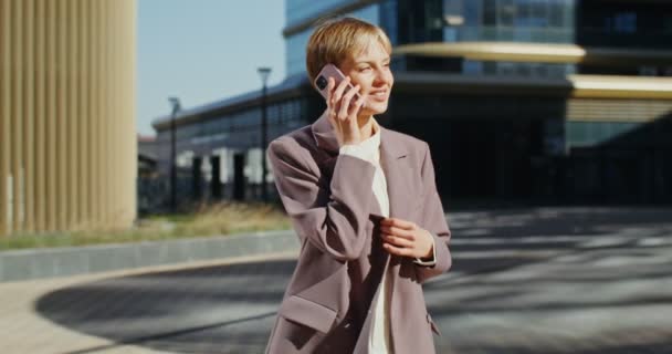Jonge vrouw in een pak van moderne snit praten op een mobiele telefoon buiten — Stockvideo