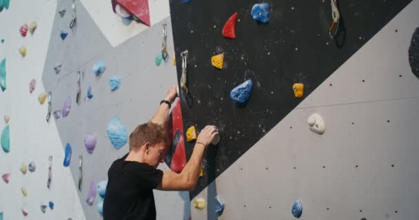 A man wearing a safety belt climbing up the climbing wall — Stock Video
