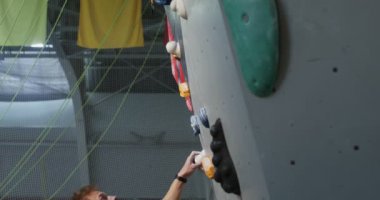 Güvenlik kemeri takan bir adam tırmanma duvarına tırmanıyor.
