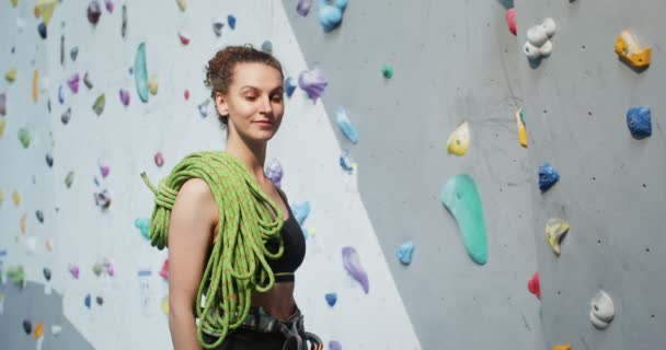 登山の壁の前に立ってカメラを見ている若い女性 — ストック動画