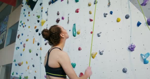 Una joven baja una cuerda de seguridad después de su propio descenso de un muro de escalada — Vídeo de stock