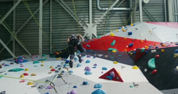 Young woman descends from the climbing wall using a roap — Stock Video