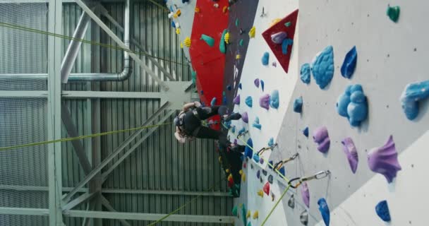 Young woman descends from the climbing wall using a roap — Stock Video