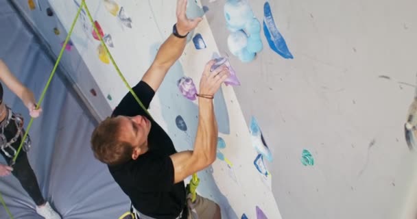 Muž vyleze na umělý povrch lezecké stěny, videozáznam shora — Stock video
