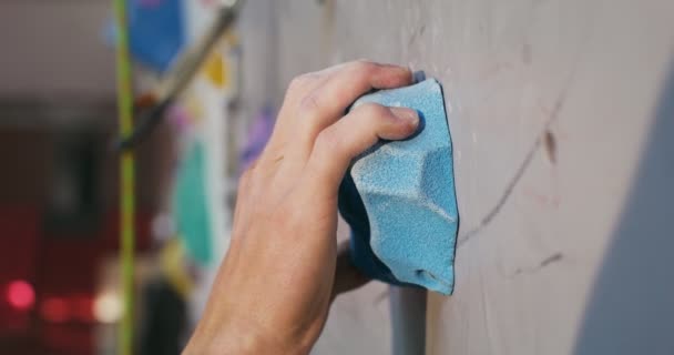 Um jovem sobe a superfície artificial da parede de escalada — Vídeo de Stock