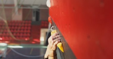 Bir adam tırmanma duvarının yapay yüzeyine tırmanır, yukarıdan video çeker.