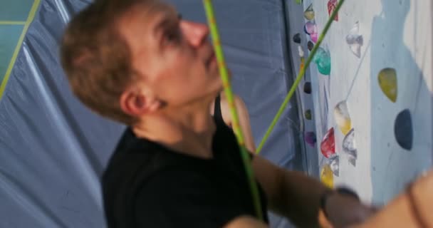 Een man klimt op een kunstmatig oppervlak van een klimwand, videoshoot van boven — Stockvideo