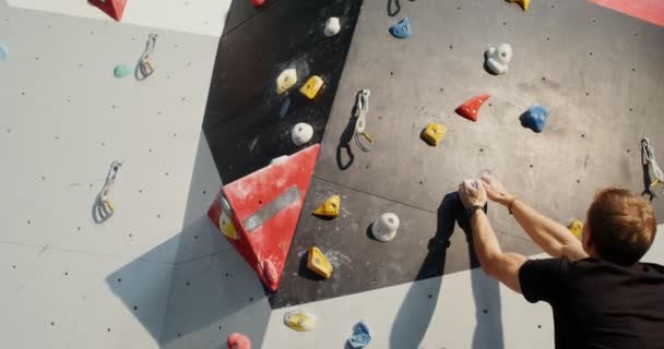 A young man climbs up the indoor climbing wall without safety ropes — Stock Video