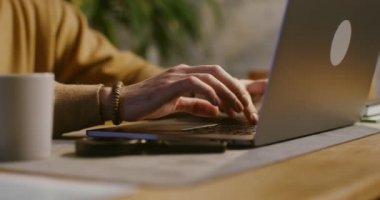Avrupalı bir adam laptopta yazı yazıyor masa başında oturuyor, yakın plan.