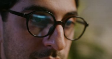 Genç adam laptopta çalışıyor. Ofisteki bir masada oturuyor.