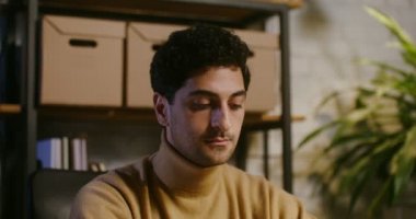 Elleriyle şakakları ovalayan, gözlerini kapatan, baş ağrısını dindiren genç bir adam.