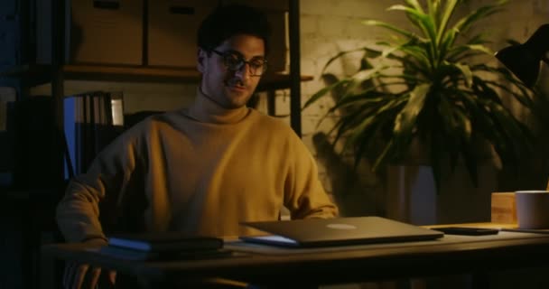 Egy fiatalember bejött az irodába éjszaka, kinyitott egy laptopot és elkezdett dolgozni. — Stock videók