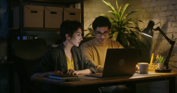 Belo jovem casal sentado na frente de um laptop aberto falando e rindo — Vídeo de Stock
