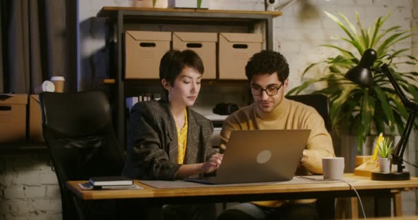 Dollar biljetten vallen van het plafond in het kantoor aan mensen die werken op een laptop — Stockvideo