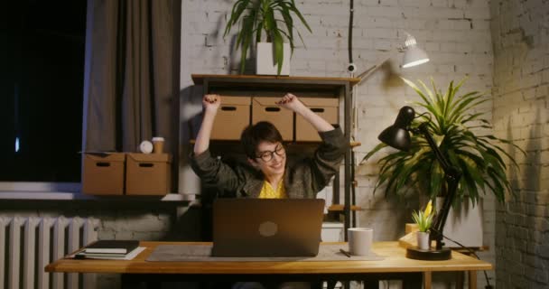 Una mujer emocionalmente se regocija y baila mientras está sentada frente a la computadora portátil — Vídeo de stock